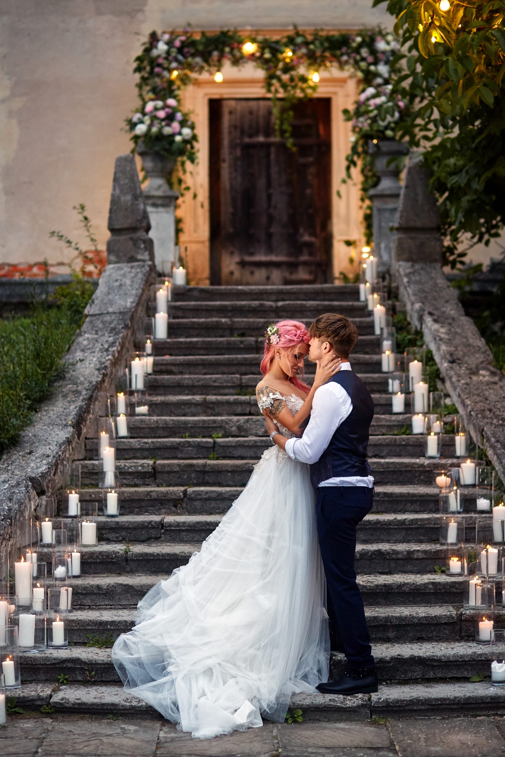 Bride with pink hair and stylish groom stand on footsteps with s Bride with pink hair and stylish groom stand on footsteps with s