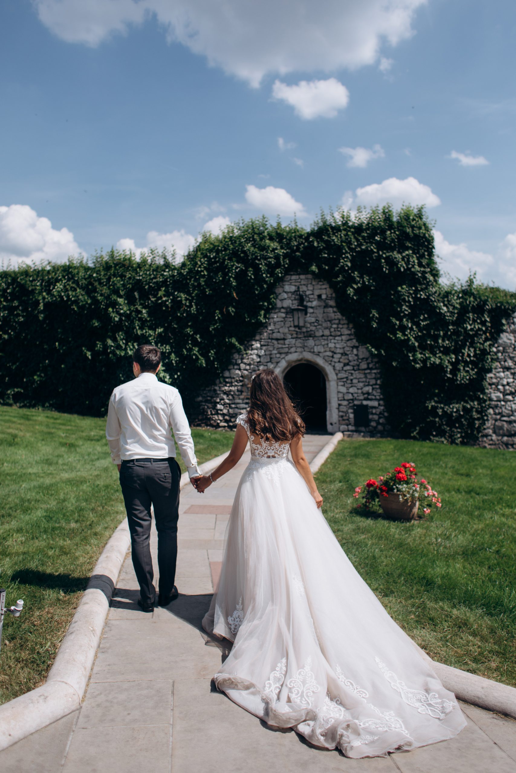Groom and a bride are holding hands and walking to a door in a s